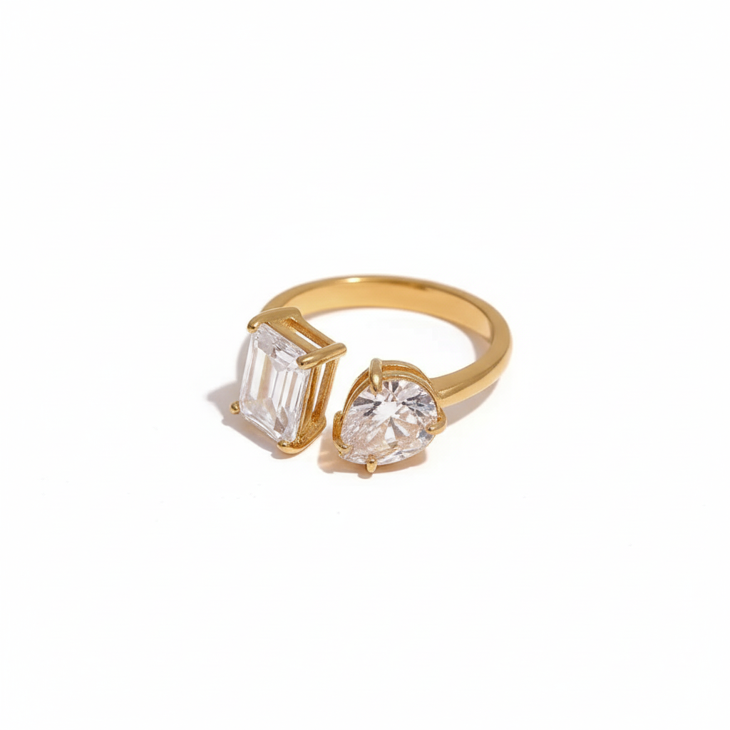 Gold open ring featuring two differently shaped clear stones one emerald-cut and one pear-cut minimalist and elegant design by Inéssi Jewelry