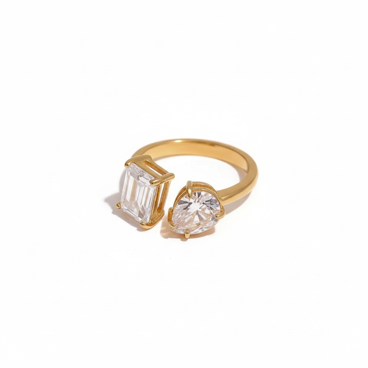 Gold open ring featuring two differently shaped clear stones one emerald-cut and one pear-cut minimalist and elegant design by Inéssi Jewelry