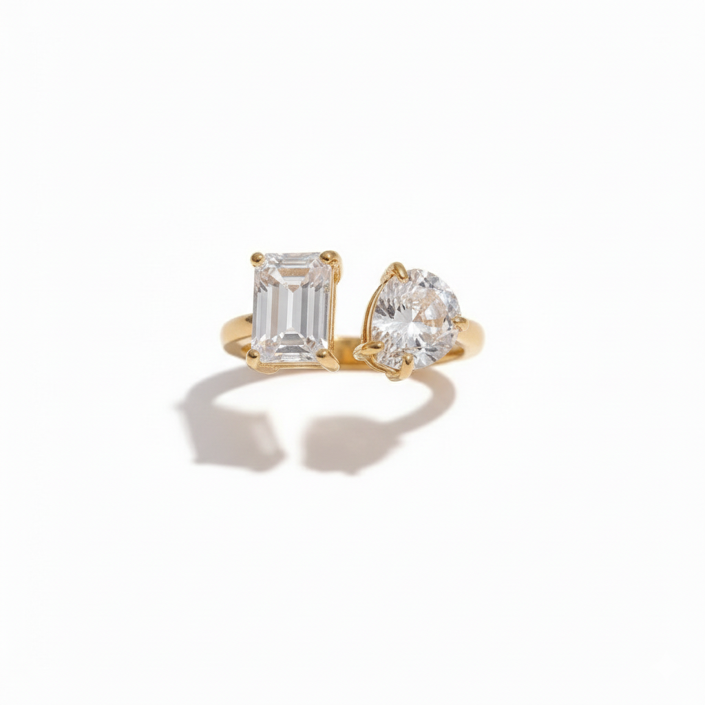 Gold open ring featuring two differently shaped clear stones one emerald-cut and one pear-cut minimalist and elegant design by Inéssi Jewelry