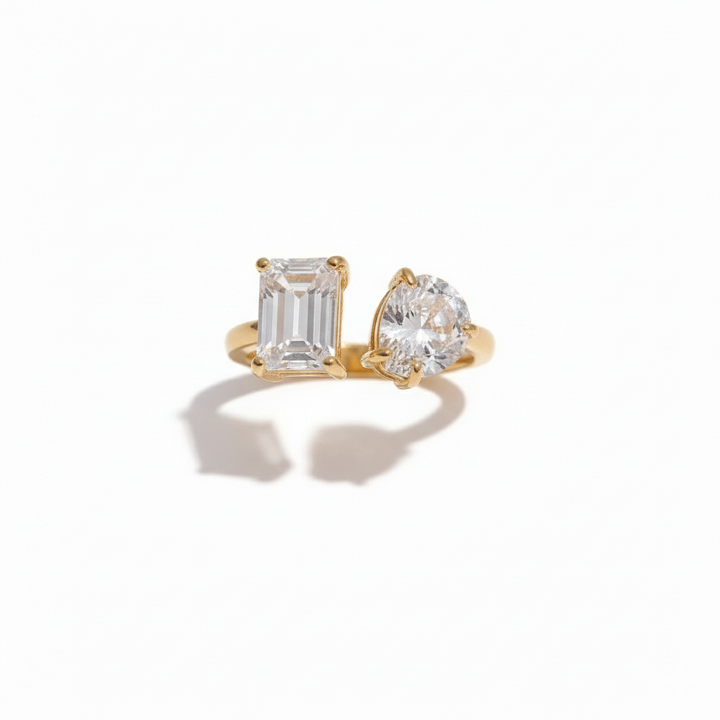 Gold open ring featuring two differently shaped clear stones one emerald-cut and one pear-cut minimalist and elegant design by Inéssi Jewelry